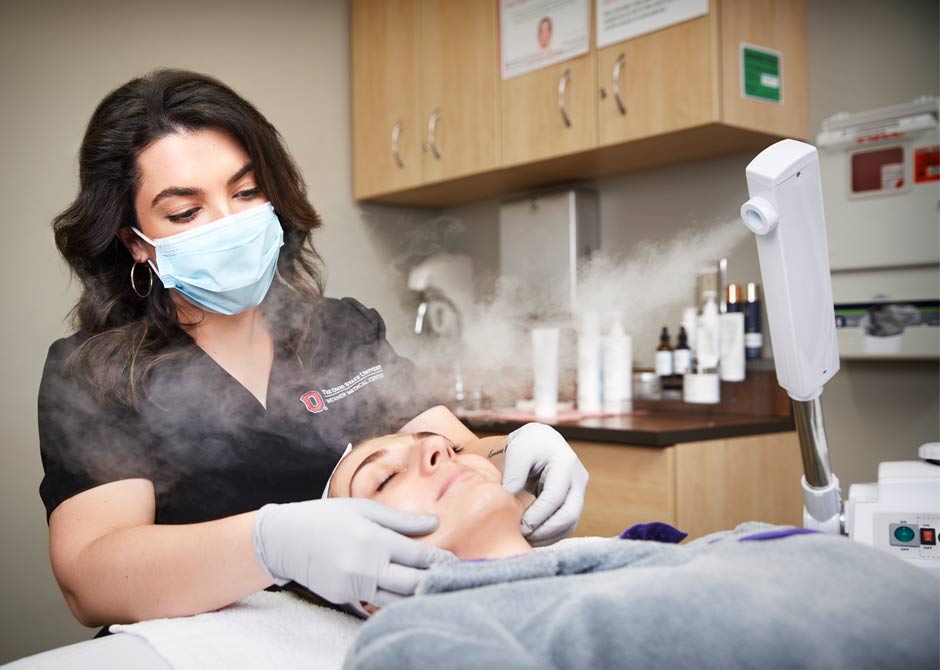Aesthetician performing a facial with steam on patient