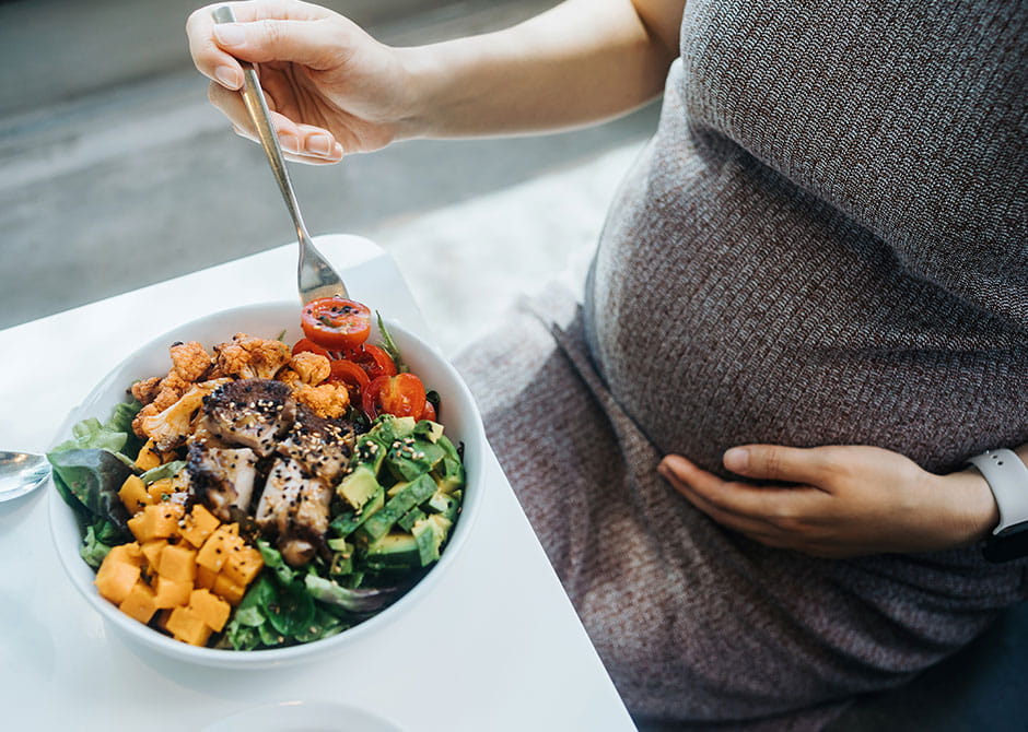 Pregnant person eating healthy bowl of colorful food
