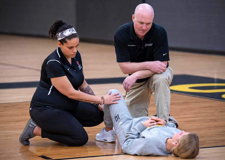 athletic trainers stretching a patient