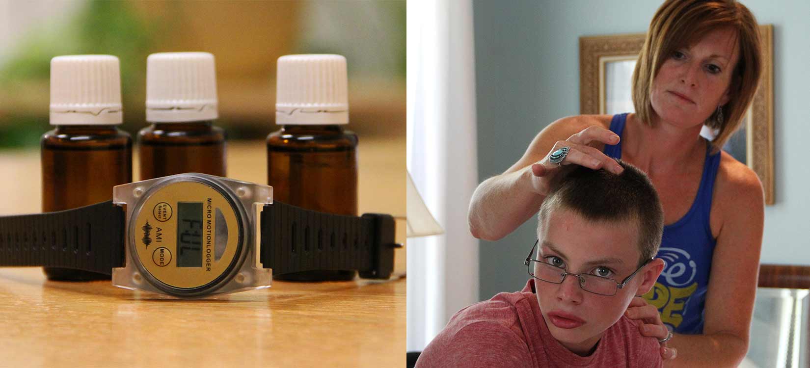 Bottles of essential oils with a watch and mother applying essential oils to son