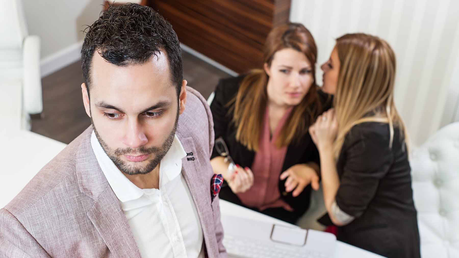 man upset by female coworkers gossiping 