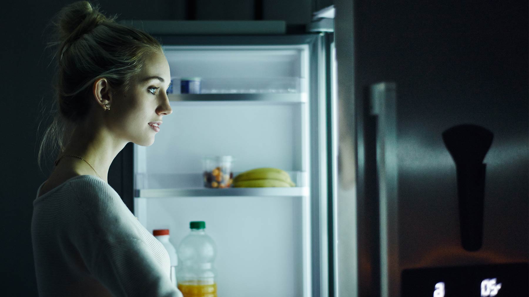 woman looking into refrigerator in the dark