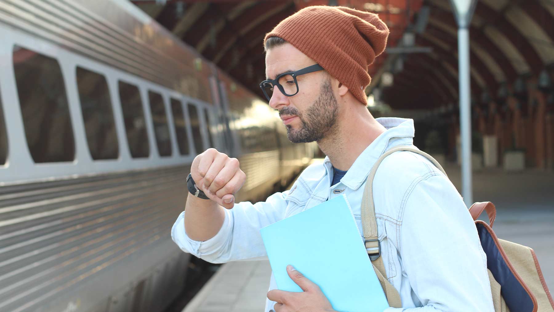 man looking at watch while waiting for train