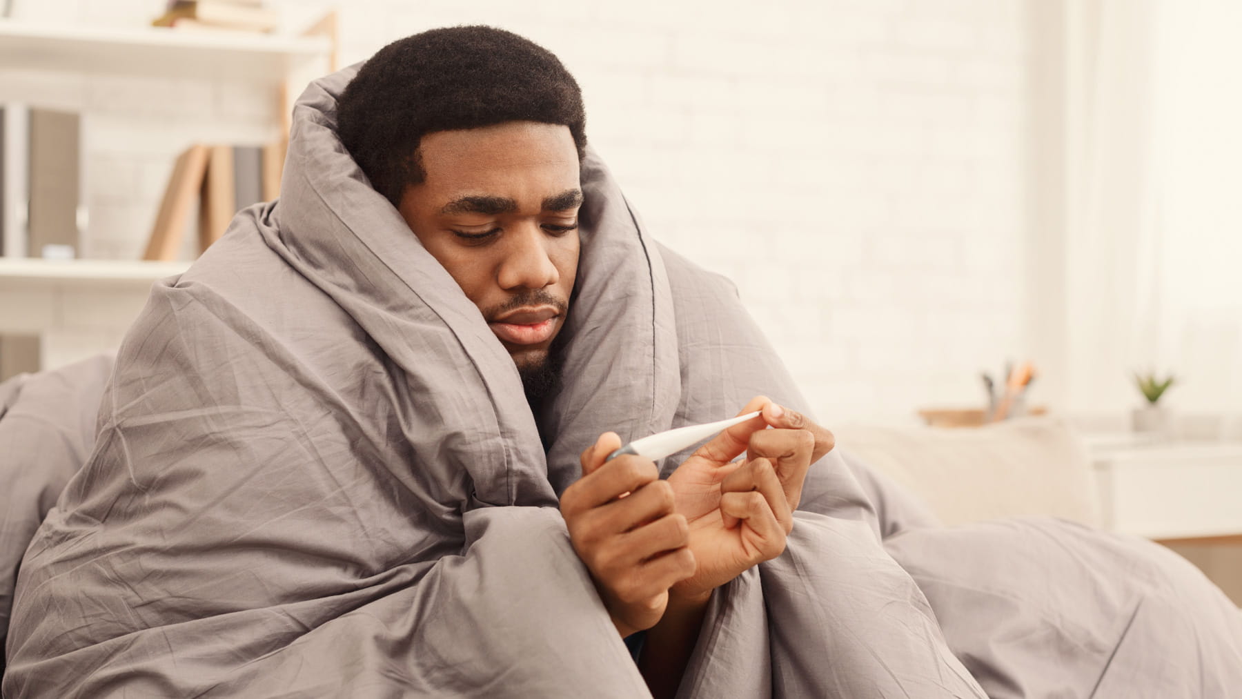 Sick man huddled under blanket