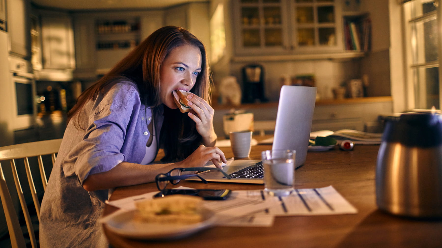 young woman eating while working at home