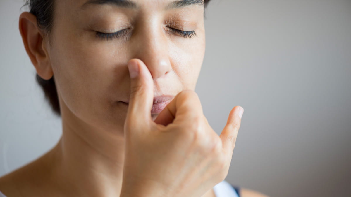 woman holding thumb to her nose