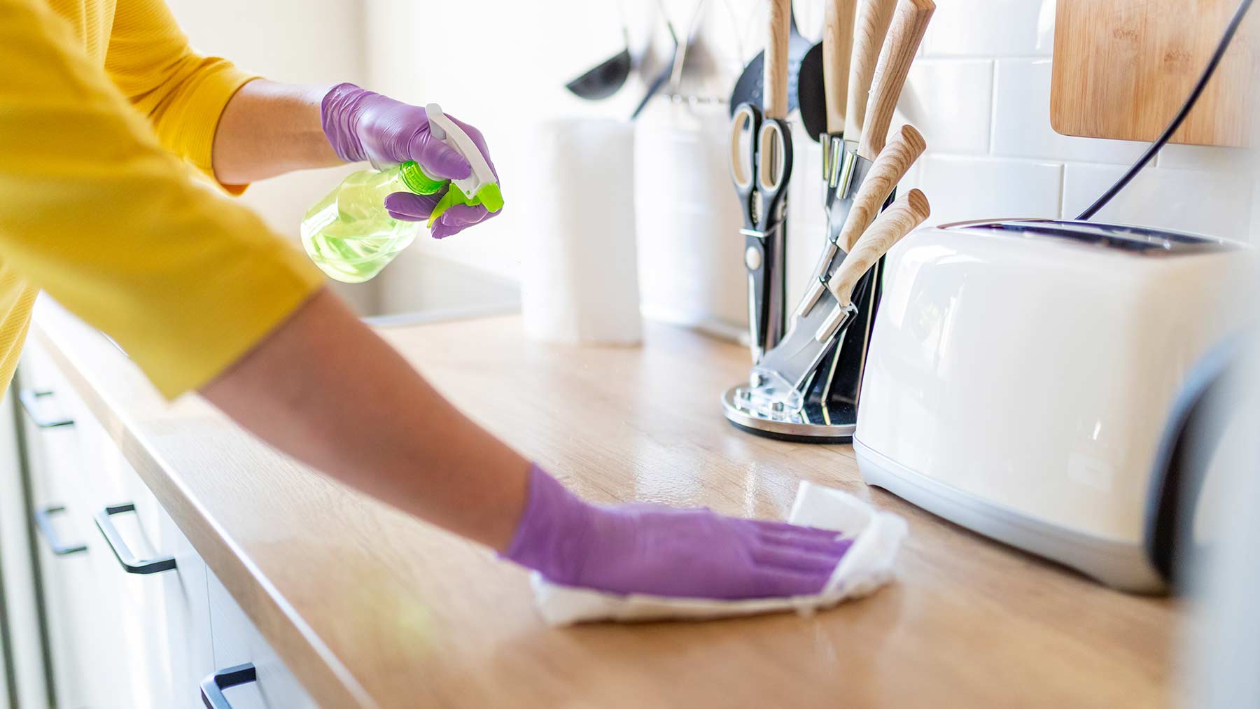 woman cleaning counter with disinfectant