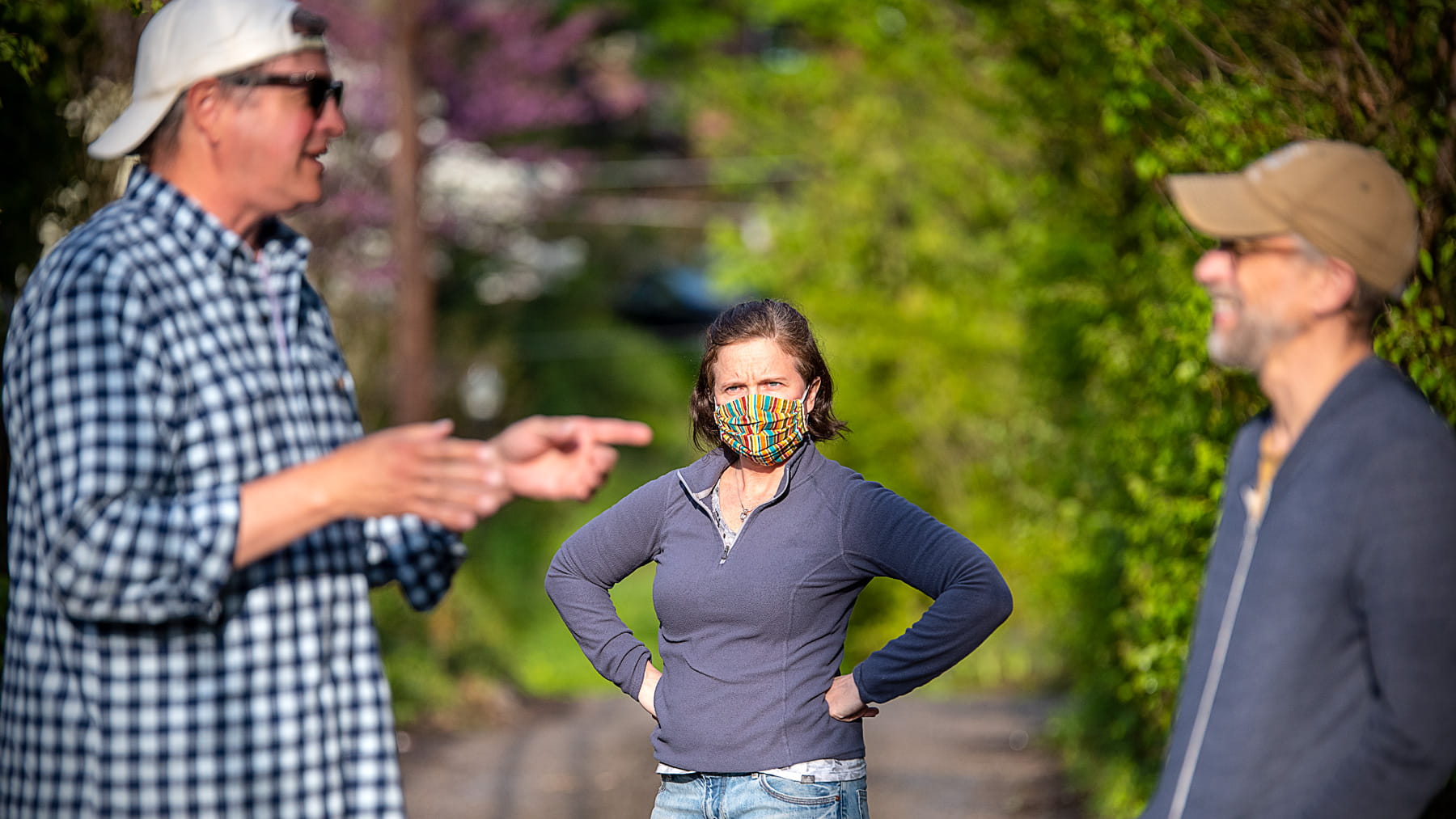 A woman looks like she disapproves of two men who are not practicing social distancing during COVID-19