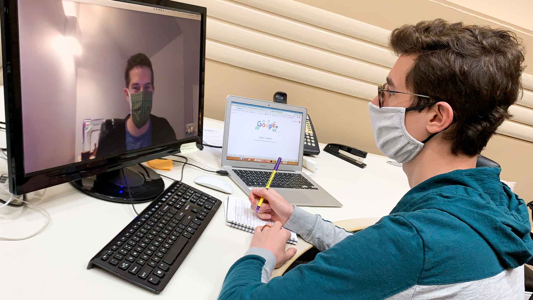man wearing a face mask while doing a video conference call at work 