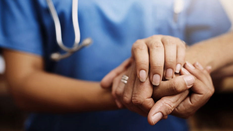 Close up image of a doctor holding a patient’s hand. 