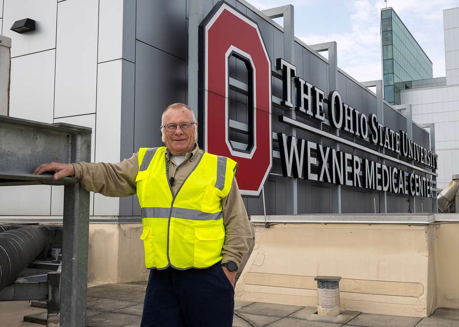 Facilities employee next to roof sign