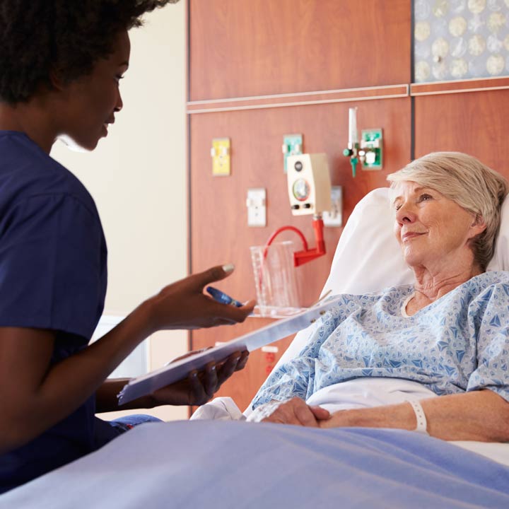 Nurse talking to a geriatric patient in hospital bed