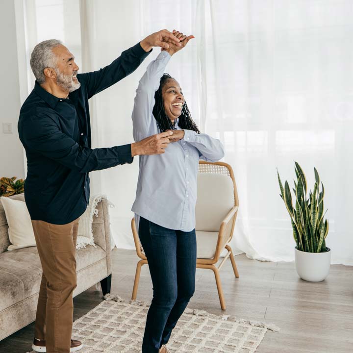 two adults dancing and laughing at home