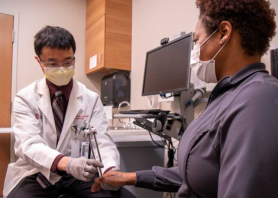 Doctor Zhang performing hand exam on patient both wearing masks