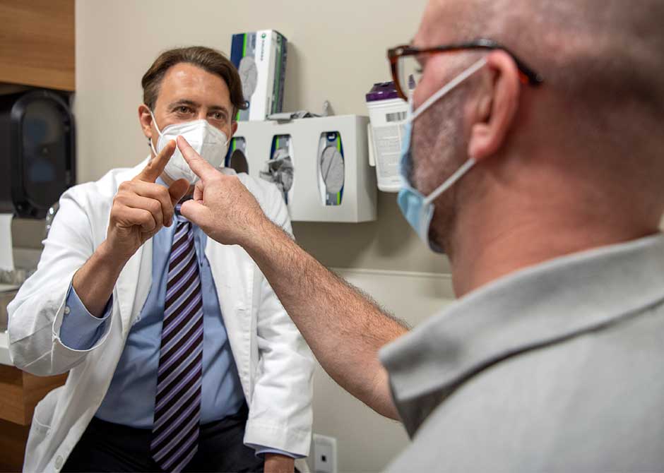 Doctor Segal and patient performing a hand motor exam both wearing masks