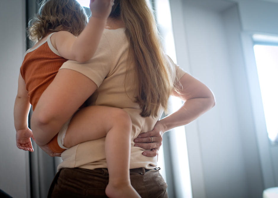 Woman with lower back pain holding a baby