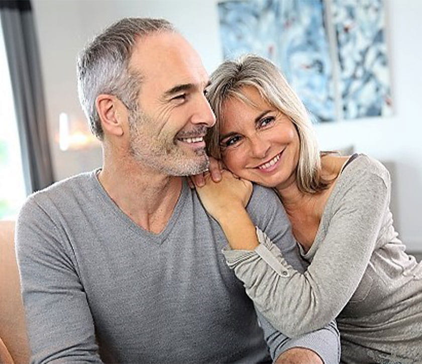 Woman hugging a man's shoulder, smiling. 