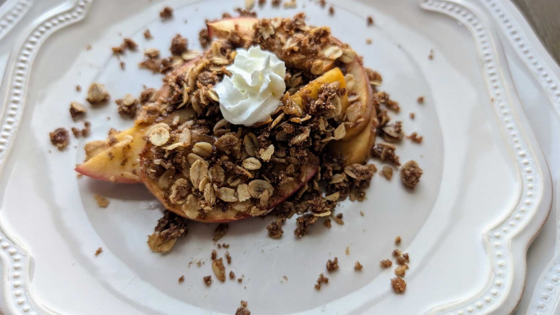 apple pie crumble with whipped cream on a white plate