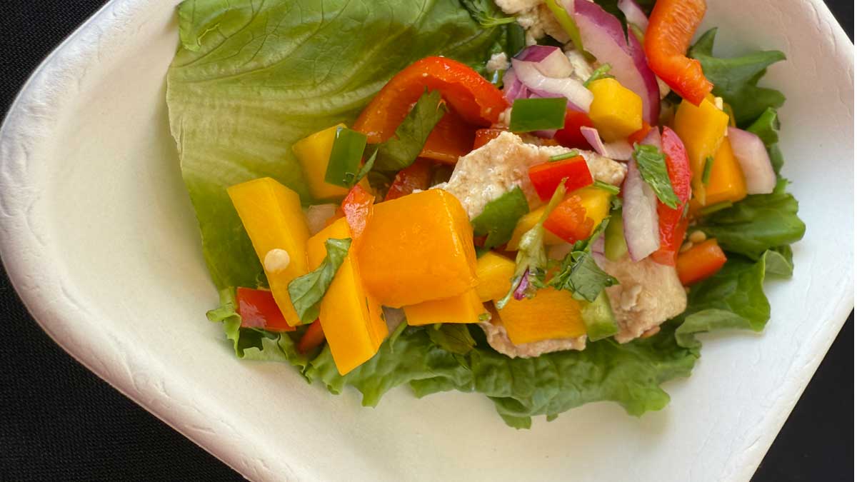 chicken lettuce wrap topped with mango salsa on a plate