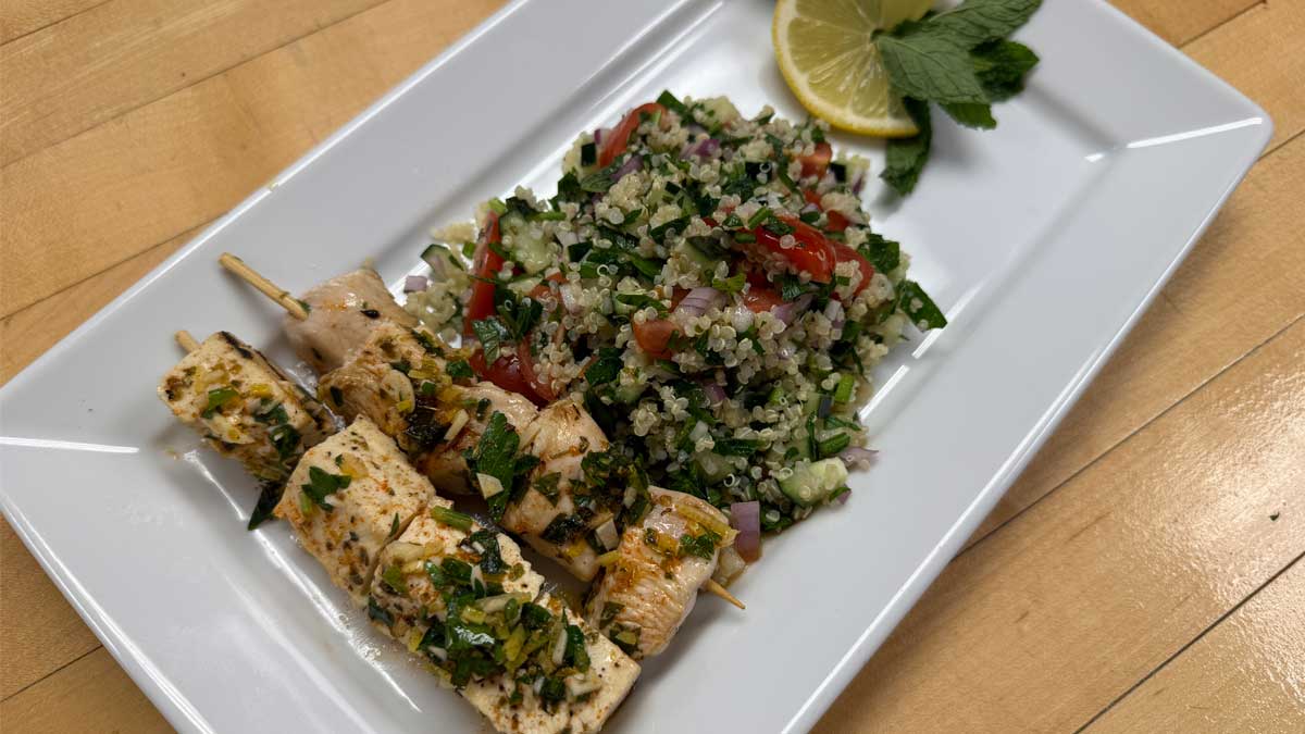 tofu and chicken skewers with quinoa tabbouleh on a plate with a lemon and mint garnish