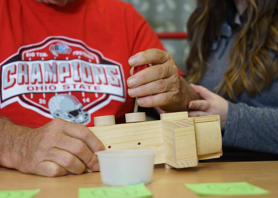 a therapist assisting a man to use a screwdriver