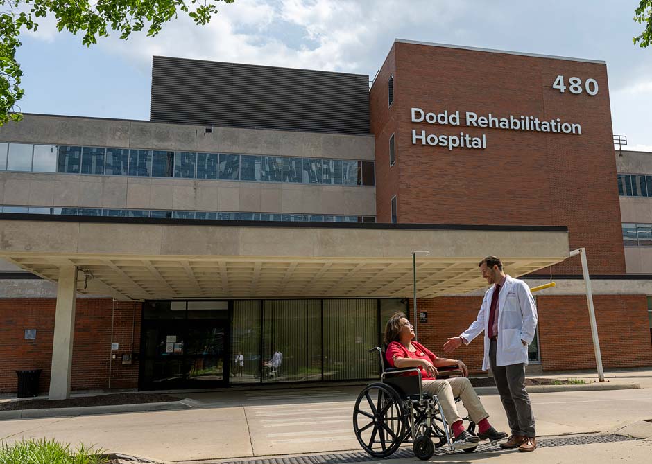 A woman in a wheelchair with her doctor outside Dodd Rehabilitation Hospital
