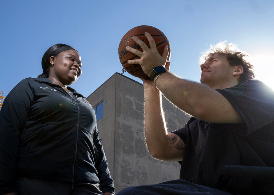 A man working with his physical therapist to throw a basketball