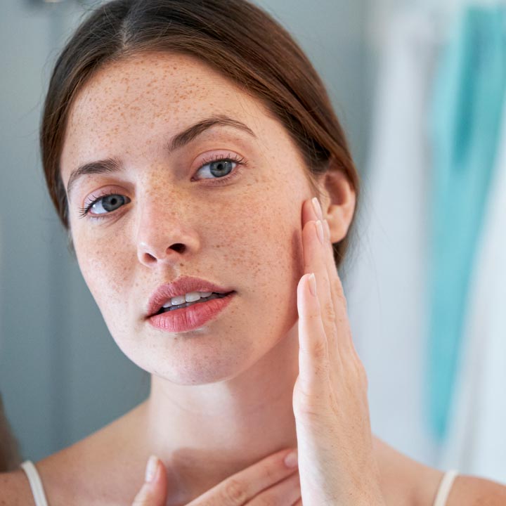 Woman touching her face after dermaplaning treatment