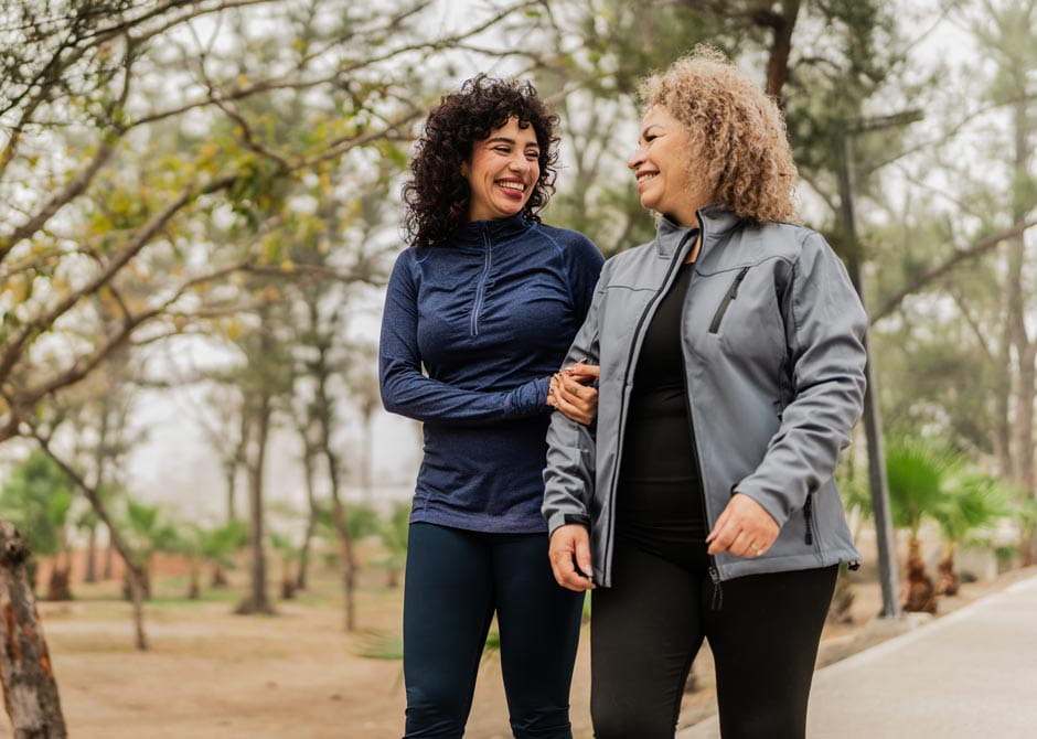 Mother and daughter talking while walking through the public park